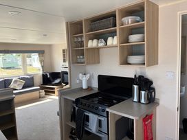 A kitchen and living area with a stove and seating at Skipsea Sands Holiday Park - Holiday Accommodation 20390, Driffield