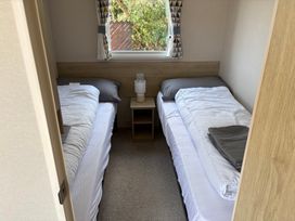 A bedroom with two beds and a bedside table at Skipsea Sands Holiday Park - Holiday Accommodation 20390, Driffield