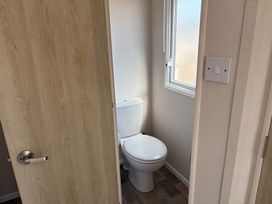 A bathroom with a toilet and window at Skipsea Sands Holiday Park - Holiday Accommodation 20390, Driffield