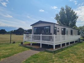A mobile home with a deck and a fence at Seashore Holiday Park - Holiday Accommodation 20465 Great Yarmouth