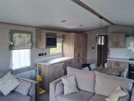 A living room with a sofa, table, and kitchen cabinets at Seashore Holiday Park - Holiday Accommodation 20465 Great Yarmouth