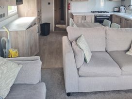 A living room with a sofa and kitchen area at Seashore Holiday Park - Holiday Accommodation 20465 Great Yarmouth