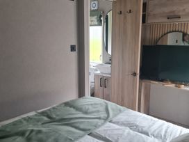 A bedroom with a bed and television at Seashore Holiday Park - Holiday Accommodation 20465 in Great Yarmouth