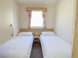 A bedroom with two single beds and a window with curtains at Golden Sands Kinmel Bay - 20528, Rhyl