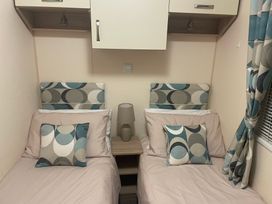 A bedroom with two beds and a bedside table at Liskey Hill Caravan Park - Holiday Accommodation 20540, Perranporth