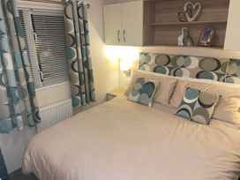 A bedroom with a bed and shelf at Liskey Hill Caravan Park - Holiday Accommodation 20540, Perranporth