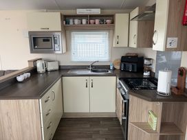 A kitchen with cabinets, sink, and appliances at Liskey Hill Caravan Park - Holiday Accommodation 20540, Perranporth