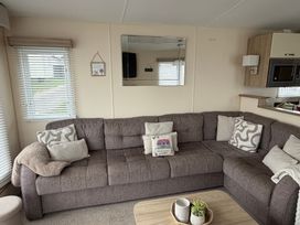 A living room with a sofa and mirror at Liskey Hill Caravan Park - Holiday Accommodation 20540, Perranporth