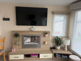 A living room with a TV and fireplace at Liskey Hill Caravan Park - Holiday Accommodation 20540, Perranporth