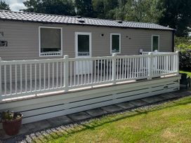 A mobile home with a deck and railing at Hafan y Mor Haven - Holiday Accommodation 20548 Pwllheli
