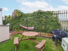 A garden with a wooden table and chairs at Golden Gate Holiday Centre - Holiday Accommodation 20618, Abergele