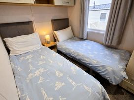 A bedroom with two single beds and a bedside table at Thornwick Bay Holiday Village - Holiday Accommodation 20633, Flamborough