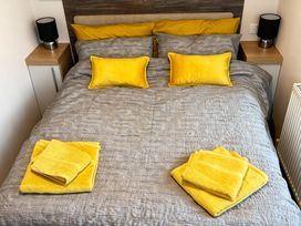 A bedroom with a bed, yellow pillows, towels and a lamp at Lyons Robin Hood - Holiday Accommodation 20871 in Rhyl