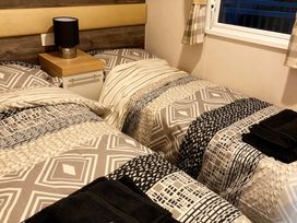 A bedroom with two single beds and a nightstand at Lyons Robin Hood - Holiday Accommodation 20871, Rhyl