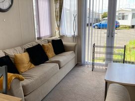 A living room with a sofa and a clock at Lyons Robin Hood - Holiday Accommodation 20871 Rhyl