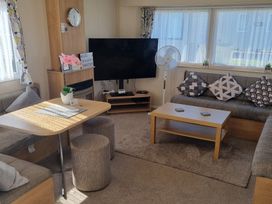 A living room with a television and a dining table at Trecco Bay - Holiday Accommodation 20876, Porthcawl