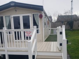A holiday home with a deck and a sign at Marton Mere Holiday Village - Holiday Accommodation 20877 Blackpool