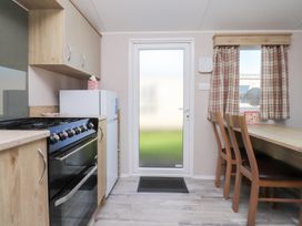 A kitchen with an oven and a dining table at Cala Gran Holiday Park - Holiday Accommodation 20962 Fleetwood
