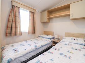 A bedroom with two single beds and a bedside table at Cala Gran Holiday Park - Holiday Accommodation 20962 Fleetwood