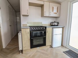 A kitchen with an oven, cupboards, fridge, and slow cooker at Ty Mawr Holiday Park - Ty Mawr