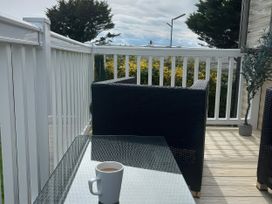 A coffee cup on a table with chairs and railing at Greenacres Holiday Park - Holiday Accommodation 21168 Porthmadog