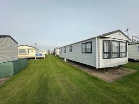 A row of caravans on a grass field at Whitehouse Leisure Park - Holiday Accommodation 21355 Towyn