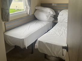 Two beds with pillows and a window in a bedroom at Cala Gran Holiday Park - Holiday Accommodation 21402, Fleetwood