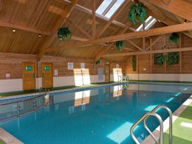 An indoor pool area with wooden ceiling and plants at Barmouth Bay Holiday Village - Holiday Accommodation 21428 Talybont