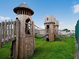 A playground with wooden towers and a rope bridge at Barmouth Bay Holiday Village - Holiday Accommodation 21428, Talybont