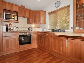 A kitchen with wooden cabinets and appliances at St Minver Holiday Park - Holiday Accommodation 21443 Wadebridge