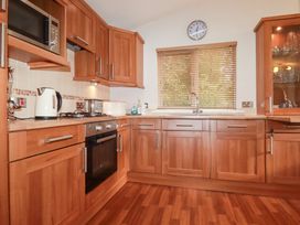 A kitchen with wooden cabinets and appliances at St Minver Holiday Park - Holiday Accommodation 21443, Wadebridge