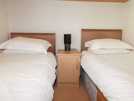 A bedroom with two beds and a nightstand at St Minver Holiday Park - Holiday Accommodation 21443 Wadebridge