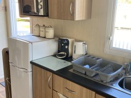 A kitchen with appliances including a refrigerator and microwave at Devon Cliffs Holiday Park - Holiday Accommodation 21624 Exmouth