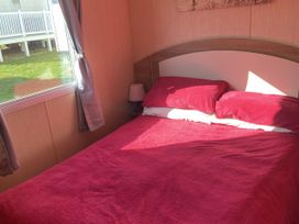 A bedroom with a bed and curtains at Devon Cliffs Holiday Park - Holiday Accommodation 21624, Exmouth
