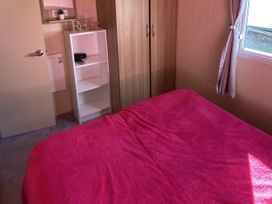 A bedroom with a bed and shelving unit at Devon Cliffs Holiday Park - Holiday Accommodation 21624 Exmouth