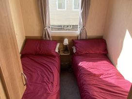 A bedroom with two beds and a lamp at Devon Cliffs Holiday Park - Holiday Accommodation 21624 in Exmouth