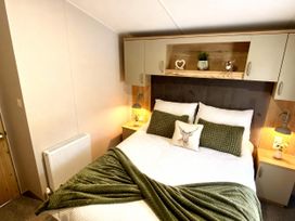 A bedroom with a bed and shelves at Aberdunant Hall Holiday Park - Holiday Accommodation 21962 in Prenteg