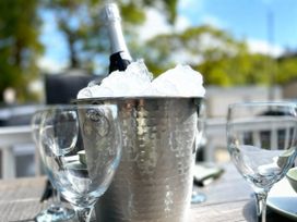 An ice bucket with champagne and wine glasses in an outdoor dining area at Aberdunant Hall Holiday Park - Holiday Accommodation 21962, Prenteg