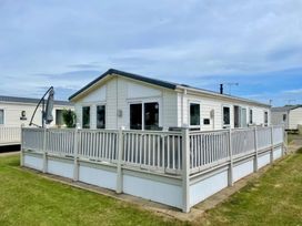 A holiday cabin with decking and outdoor furniture at Manor Park Holiday Village - Holiday Accommodation 22030 Hunstanton