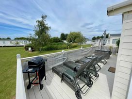 An outdoor area with deck chairs and a barbecue grill at Manor Park Holiday Village - Holiday Accommodation 22030 Hunstanton