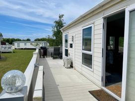 A deck area with chairs and barbecue at Manor Park Holiday Village - Holiday Accommodation 22030 Hunstanton