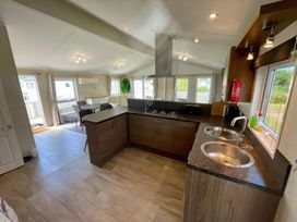 A kitchen with a stove and dining table at Manor Park Holiday Village - Holiday Accommodation 22030, Hunstanton