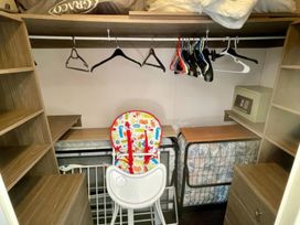 A closet with shelves and a high chair at Manor Park Holiday Village - Holiday Accommodation 22030 Hunstanton