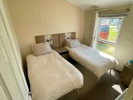 A bedroom with two single beds and a window at Manor Park Holiday Village - Holiday Accommodation 22030 Hunstanton