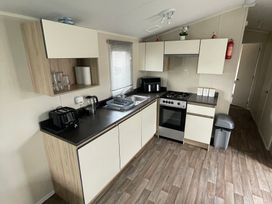 A kitchen with cabinets, sink, stove, and various appliances at Golden Gate Holiday Centre - Holiday Accommodation 22147 Towyn