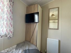 A bedroom with a TV and a mirror at Golden Gate Holiday Centre - Holiday Accommodation 22147 Towyn