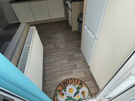 A kitchen with cabinets and a fridge at Golden Gate Holiday Centre - Holiday Accommodation 22147 in Towyn