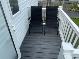 An outdoor seating area with two black chairs and a door at Golden Gate Holiday Centre - Holiday Accommodation 22147 Towyn