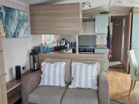 A living room with a sofa and kitchen area at Ty Gwyn Caravan Park - Holiday Accommodation 22189 Abergele