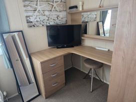 A desk with a television and mirror in a bedroom at Ty Gwyn Caravan Park - Holiday Accommodation 22189 Abergele